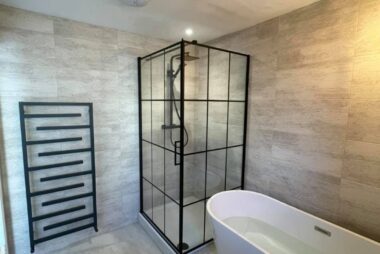 Modern bathroom with a black-framed walk-in shower enclosure, complete with a rainfall shower system and minimalist black fixtures.