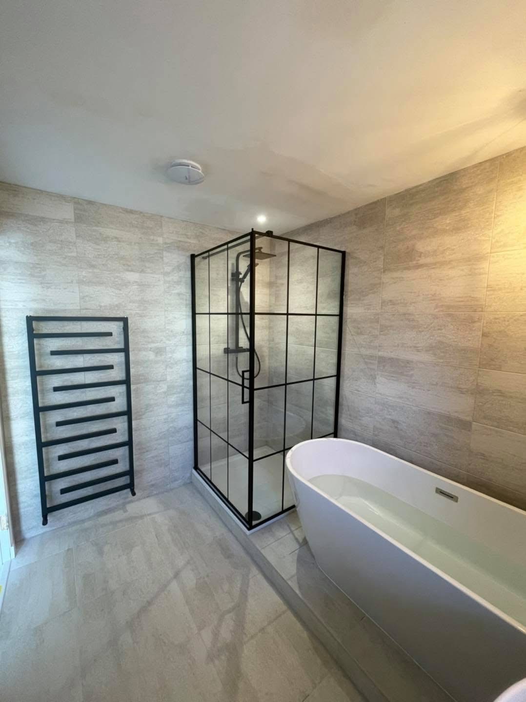Modern bathroom with a black-framed walk-in shower enclosure, complete with a rainfall shower system and minimalist black fixtures.